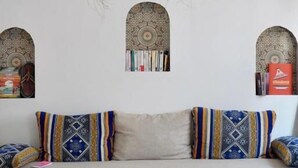 Una habitación con sofá, cojines estampados, una lámpara colgante tejida y decoración en la pared.