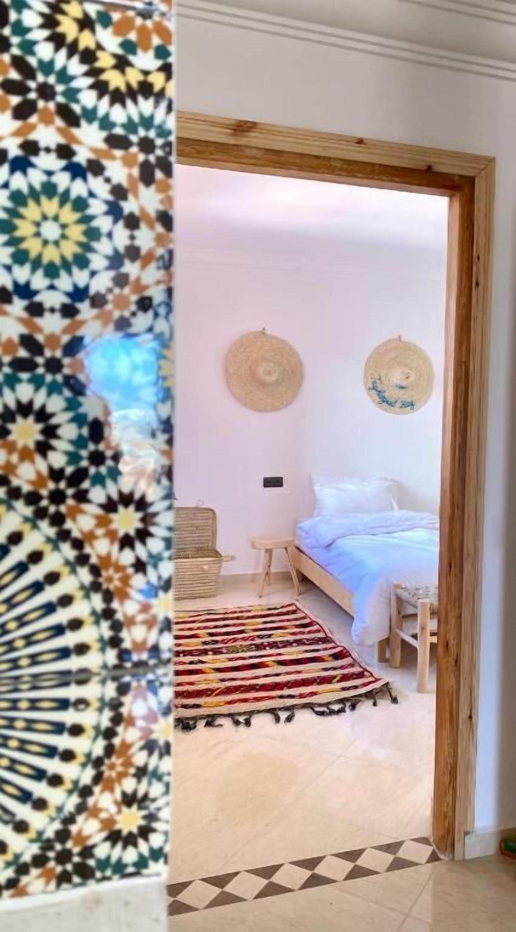 A room with a bed, a small table, and a wall-mounted lamp.
