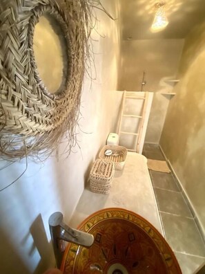 A bathroom with a woven wall decoration, a small woven basket, a towel, and a patterned basin. - Moana Surf Maroc (Aourir)