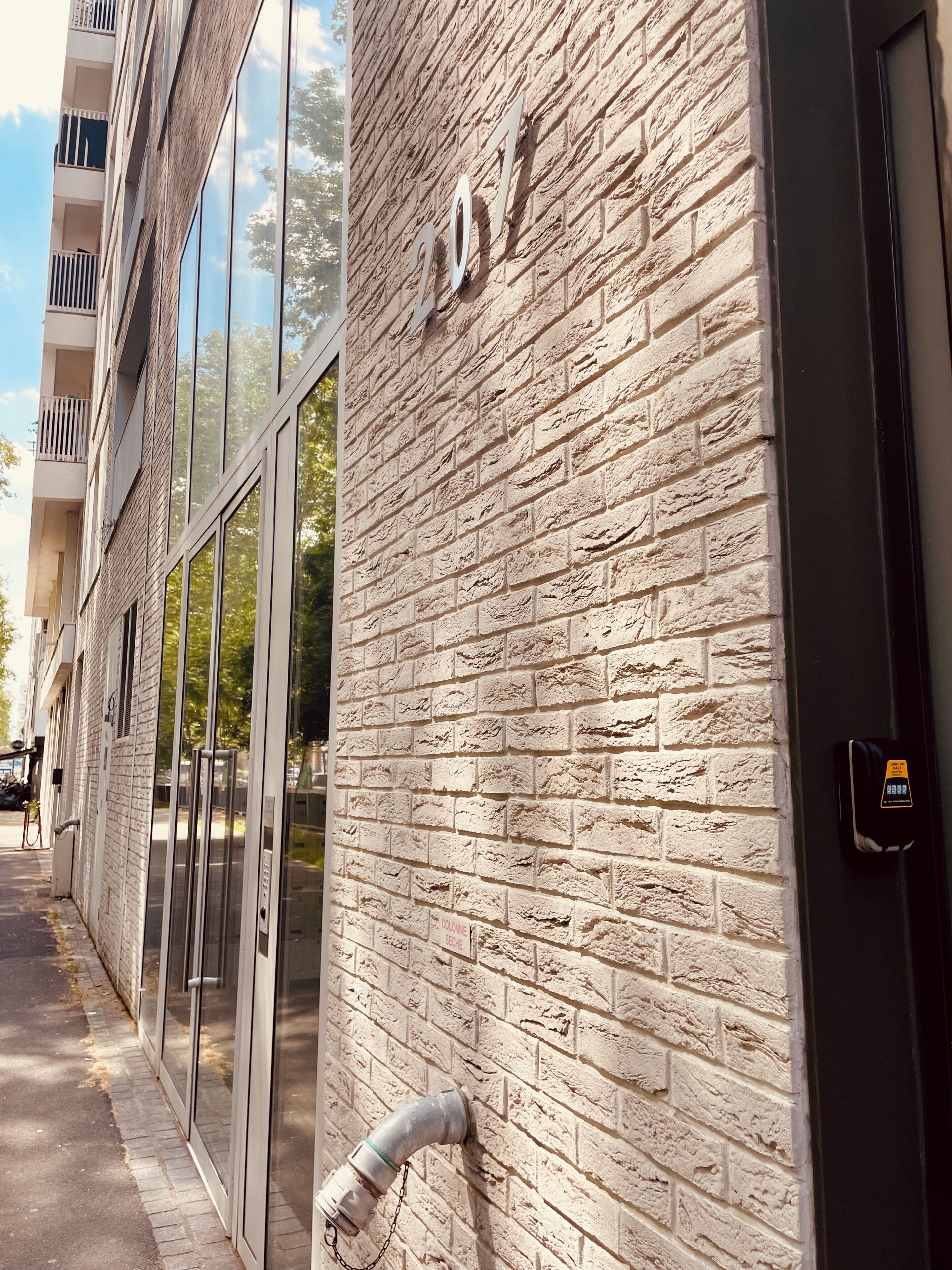 Fachada de edificio con pared de ladrillo y una puerta que dice 'COLONIE SECHE'.