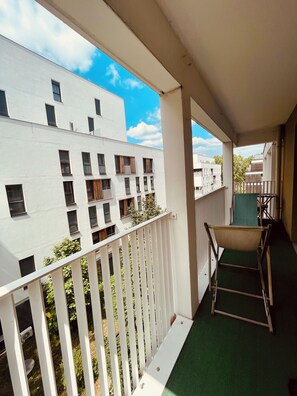 A balcony with a white railing, a green mat, and a chair. - A cozy and spacious apartment just outside Paris. Perfect for families. (Noisy-le-Sec)