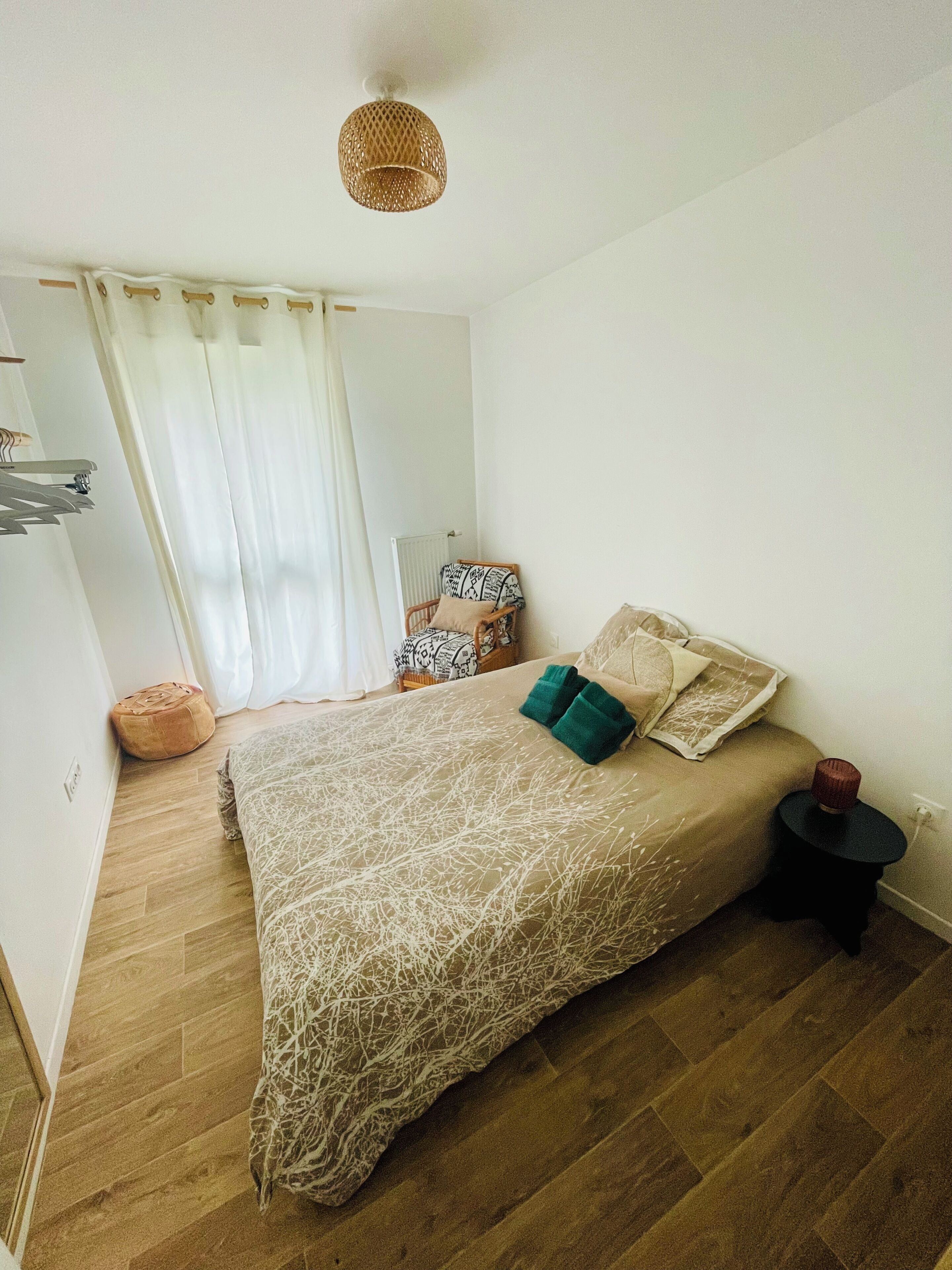 Un dormitorio con cama, una mesita auxiliar, una silla, un radiador y una lámpara colgante.