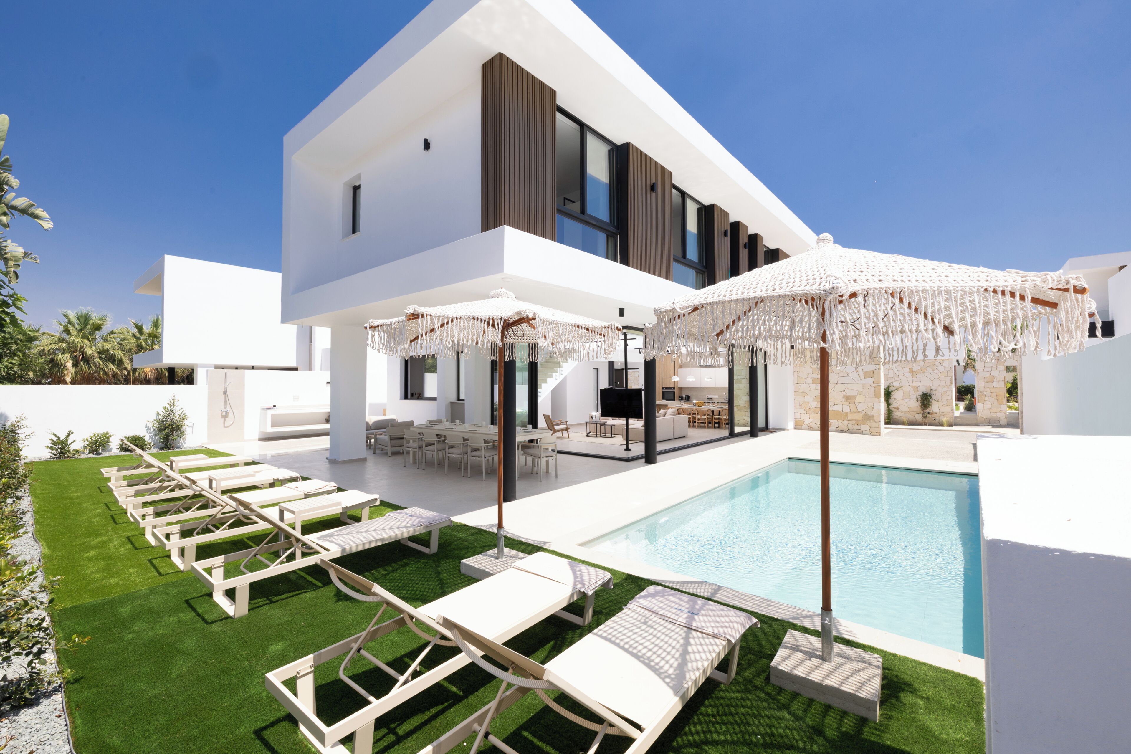 Una casa moderna con piscina, area salotto esterna e prato curato.
