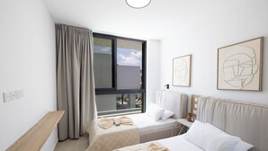 A hotel room with two beds, a window with curtains, a bedside table, and artwork on the wall. - New, 4 Bedroom Villa With Pool, 100 Meters From the Beach (Paralimni)