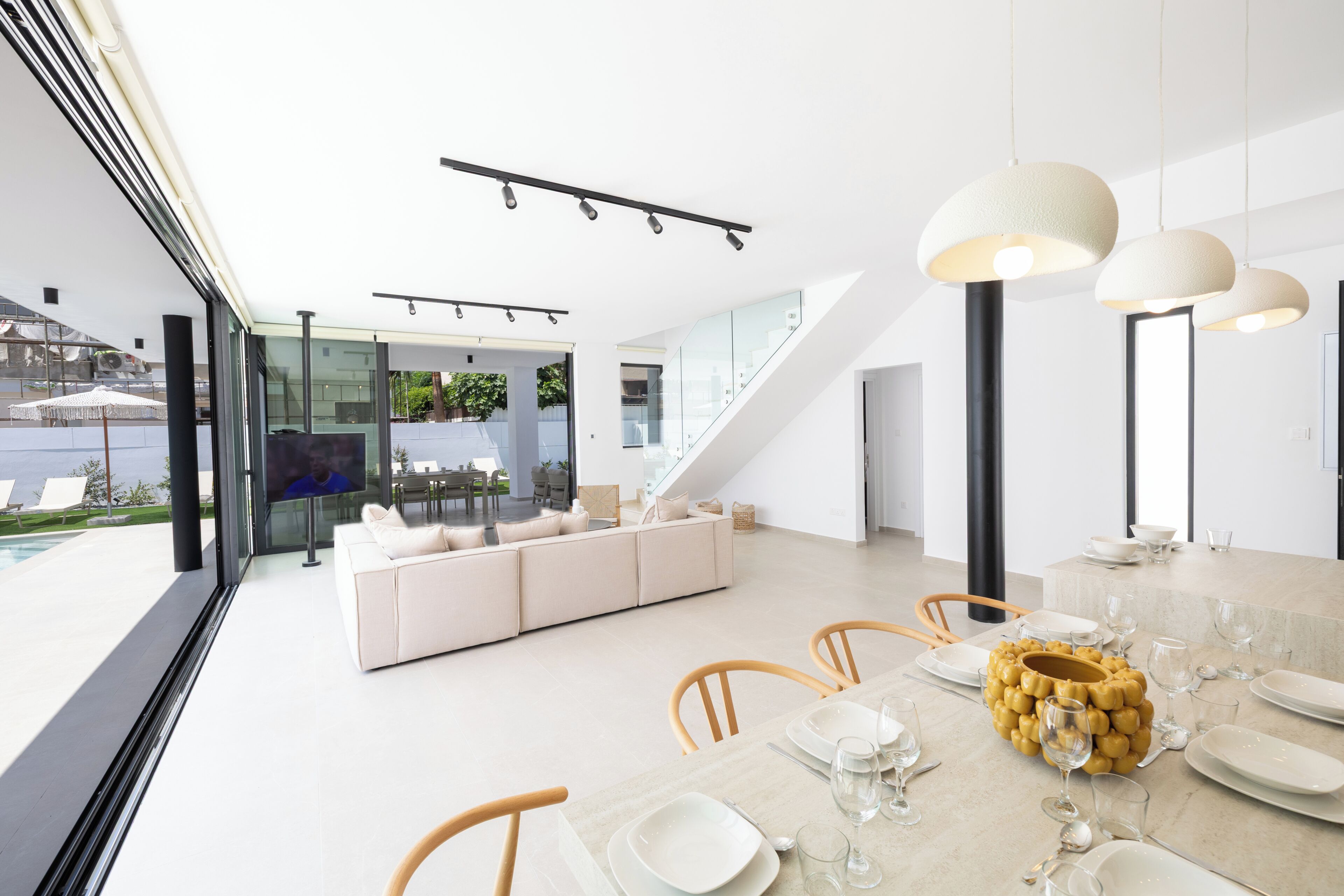 A modern interior with a dining area, sofa, and a view of the outdoors.