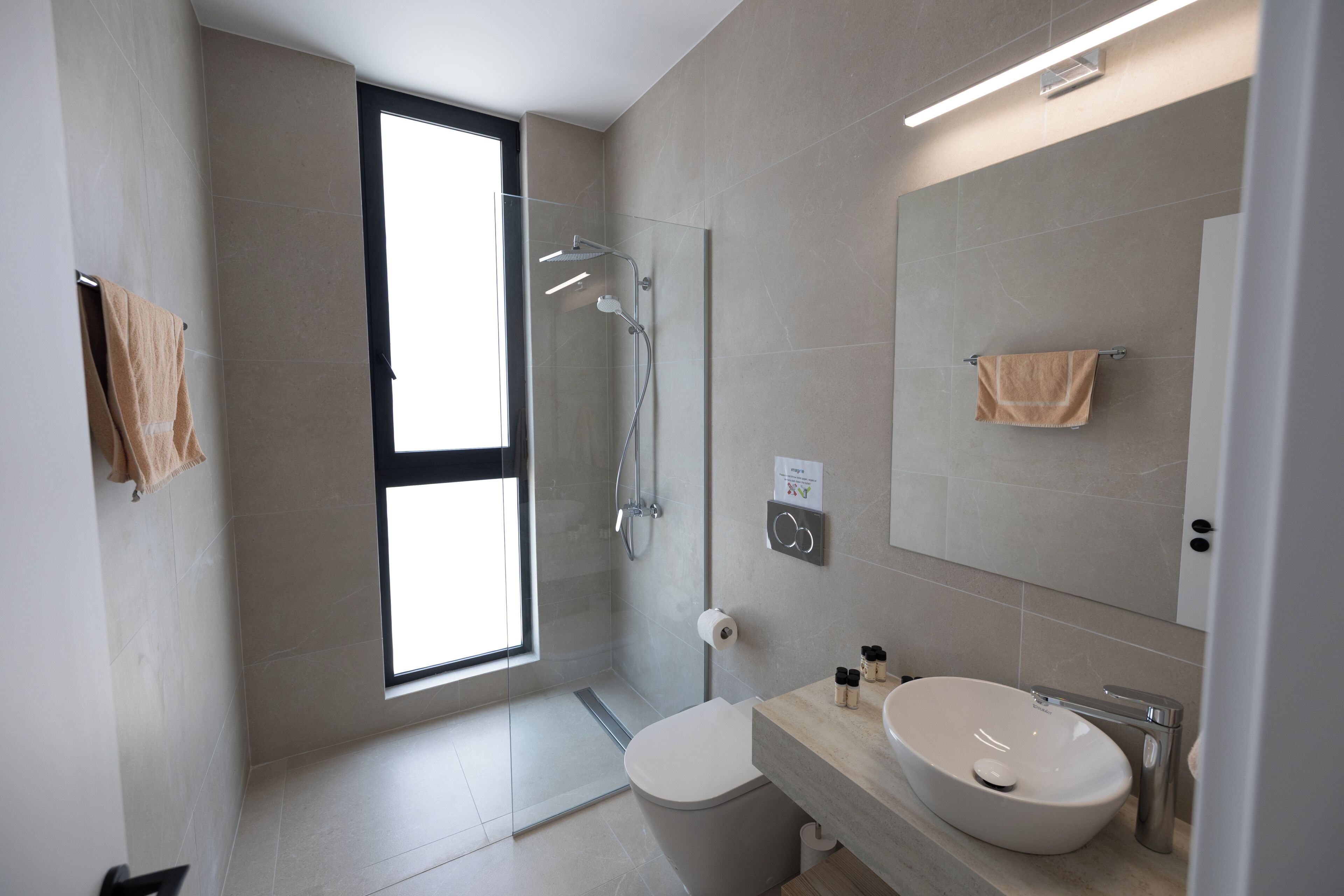 A modern bathroom with a shower, toilet, and sink.