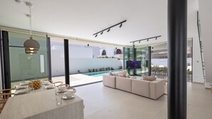 A modern interior with a dining area, a pool, and a seating area. - New, 4 Bedroom Villa With Pool, 100 Meters From the Beach (Paralimni)