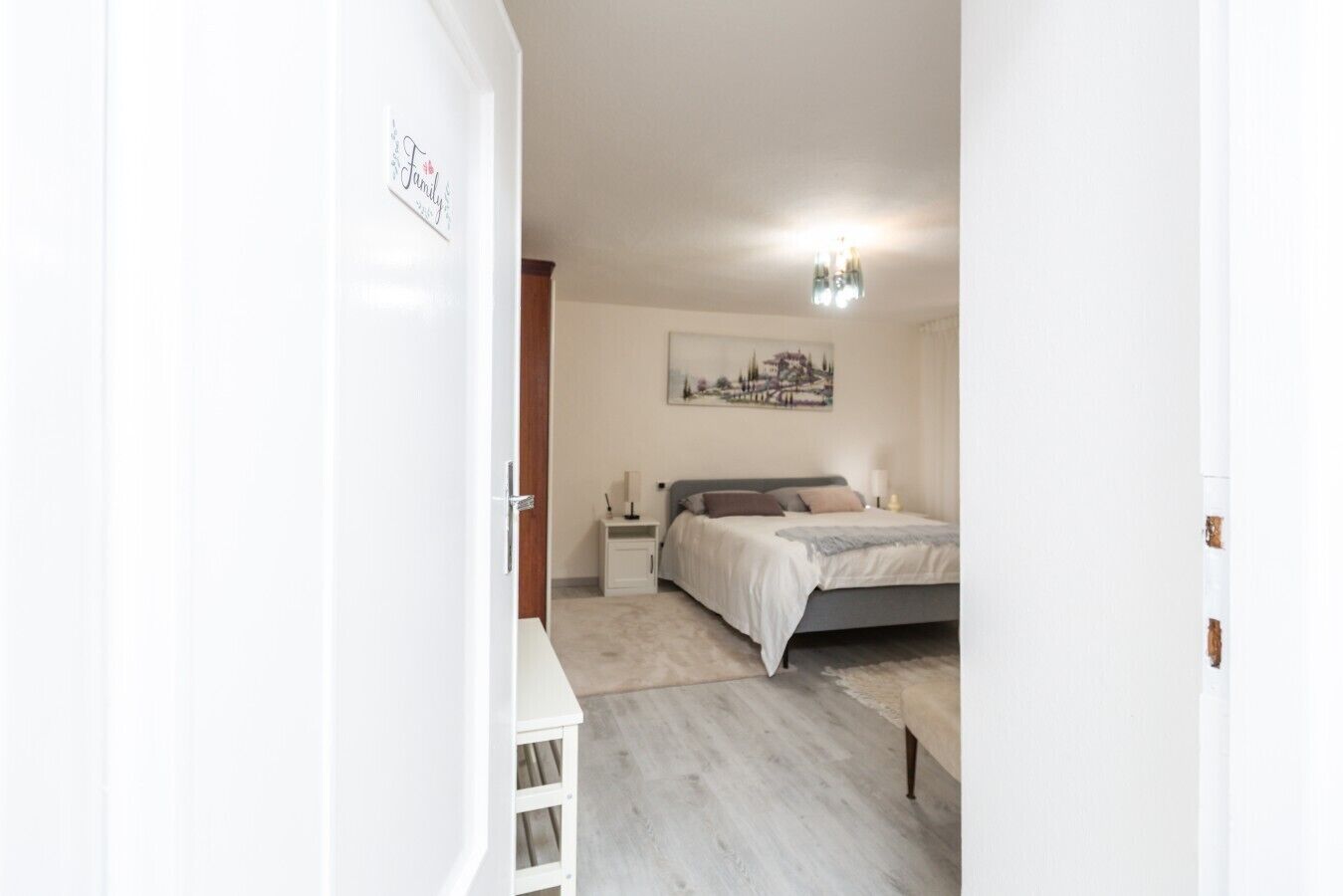 Un dormitorio con cama, mesitas de noche, lámpara de pared y un cuadro.