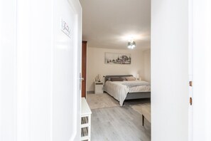 Ein Schlafzimmer mit einem Bett, Nachttischen, einer Wandlampe und einem Gemälde.