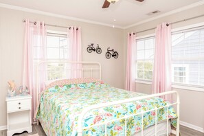 A bedroom with a bed, a nightstand, a wall-mounted bicycle decoration, and a window with curtains. - Big Fish - Classic 4BR Oceanfront Home - Covered Porch (Topsail Beach)
