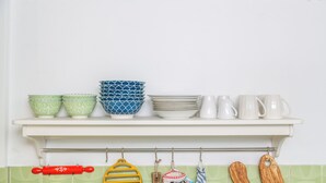 A kitchen shelf with various bowls, plates, and utensils.