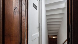 A wooden door with a sign indicating a toilet, leading to a staircase with white walls and a wooden handrail.