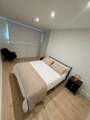 A bedroom with a bed, a chair, a nightstand, and a mirror. - 1 Luxury 1-Bed | Sleeps 4 | Free Parking, Gym, Cinema, Games Room, Lounge + More (London)