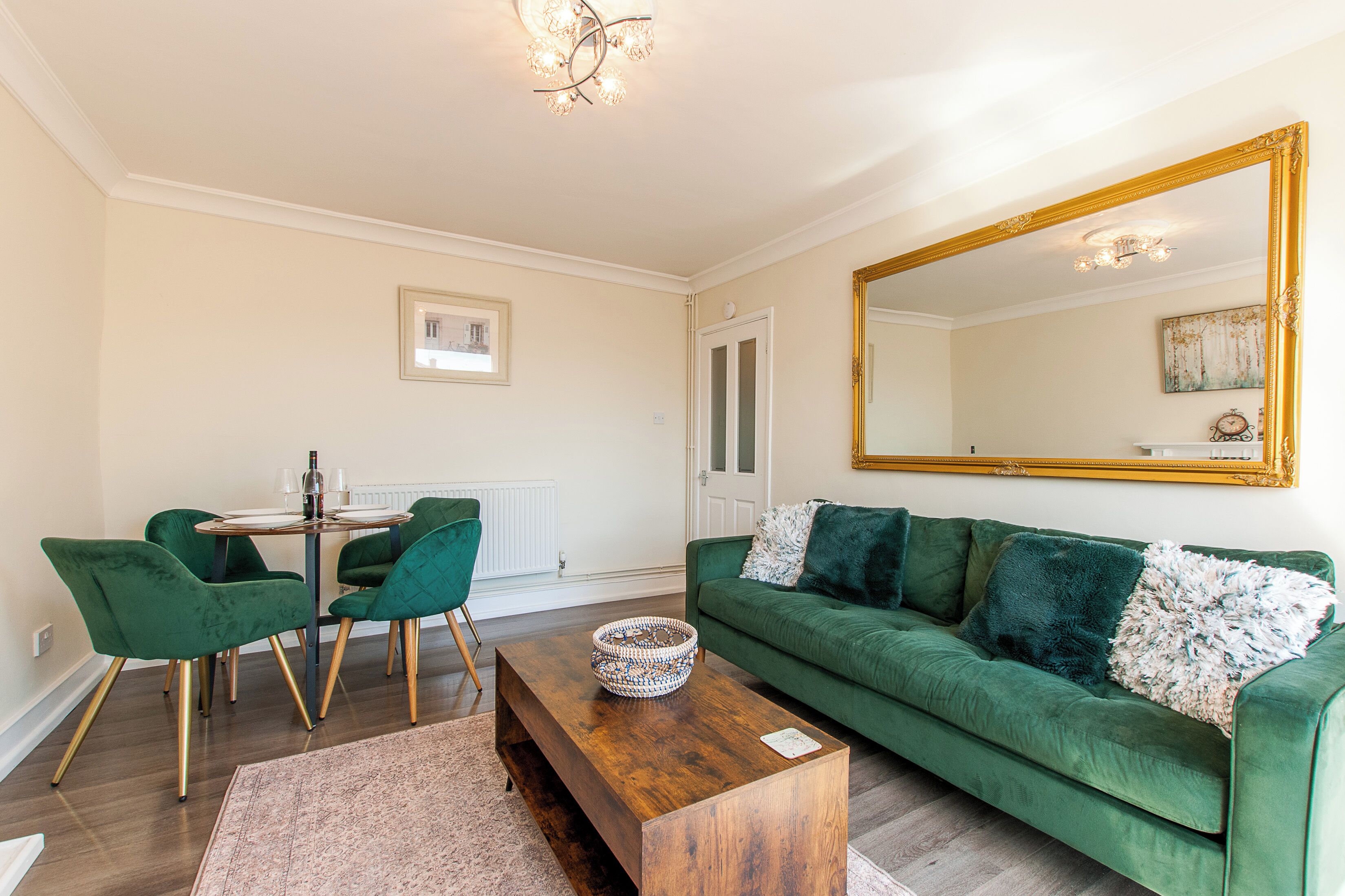 Ein Wohnzimmer mit einem grünen Sofa, einem Holztisch und einem Essbereich mit grünen Stühlen.
