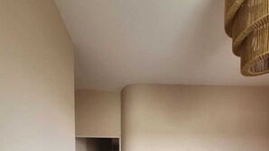 A bedroom with a bed, a wooden floor, and a hallway leading to another room.