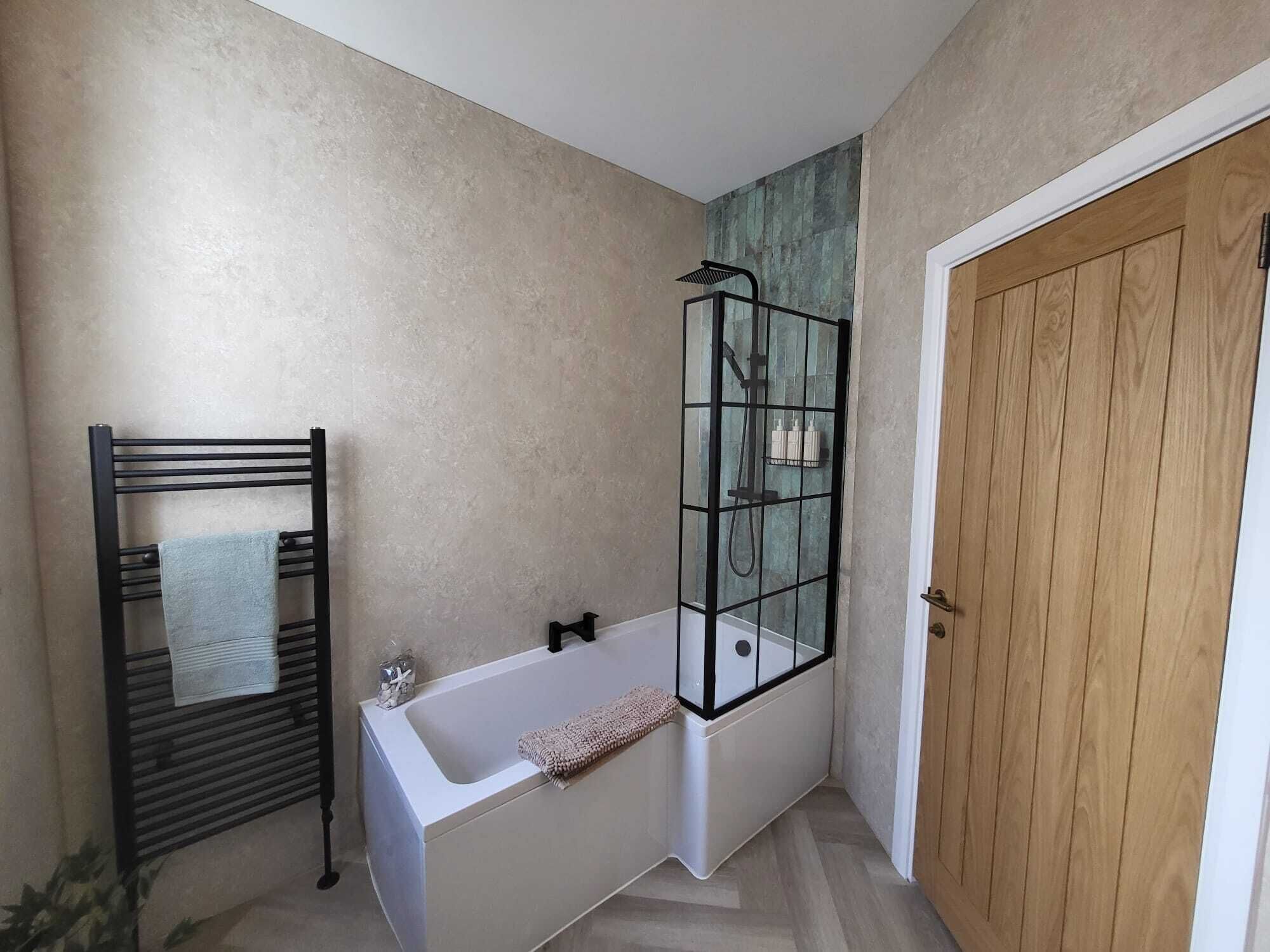 Une salle de bain avec une baignoire, une douche à parois de verre et une porte en bois.