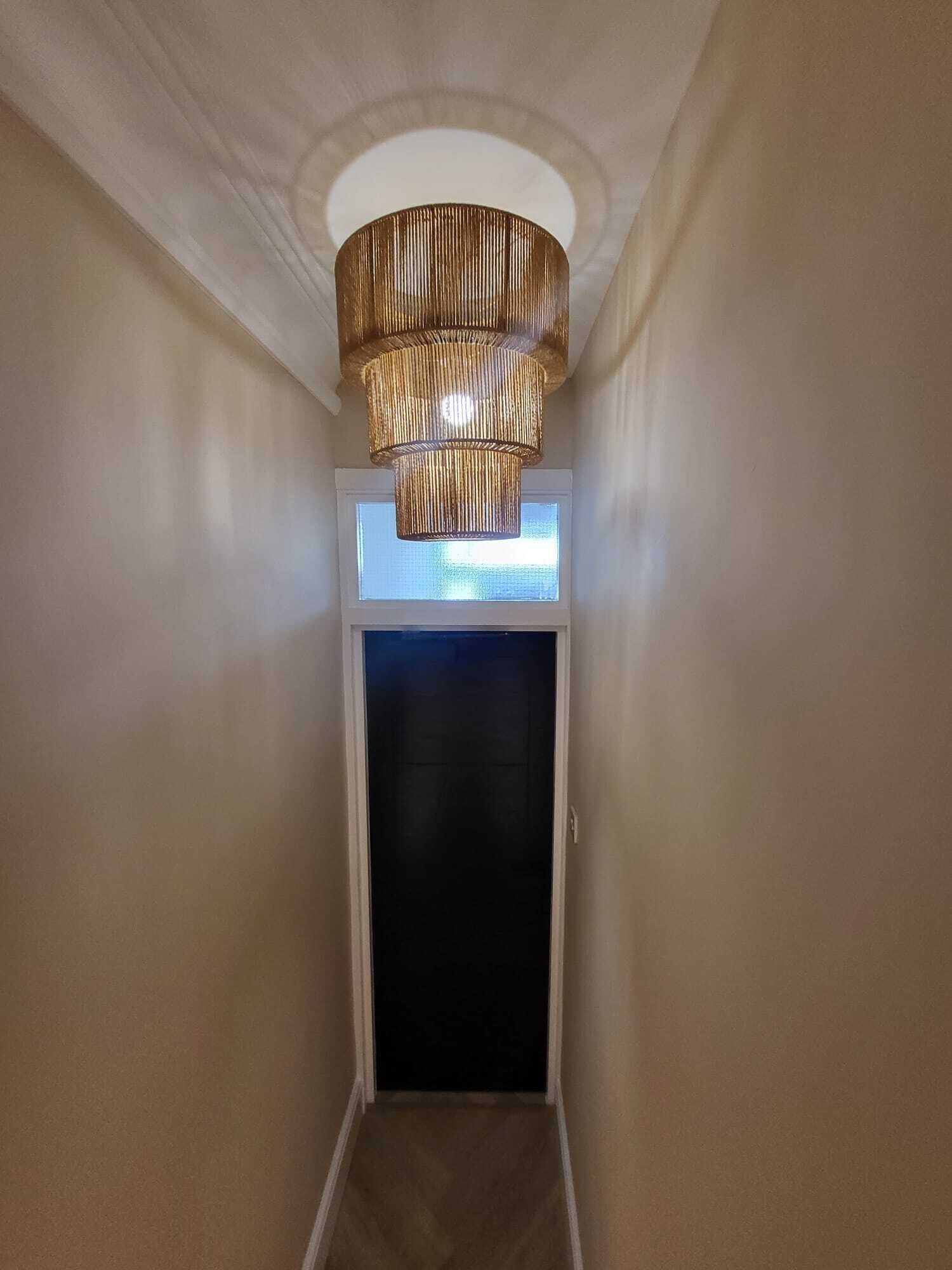 A hallway with a textured, cylindrical ceiling light fixture and a door at the end.