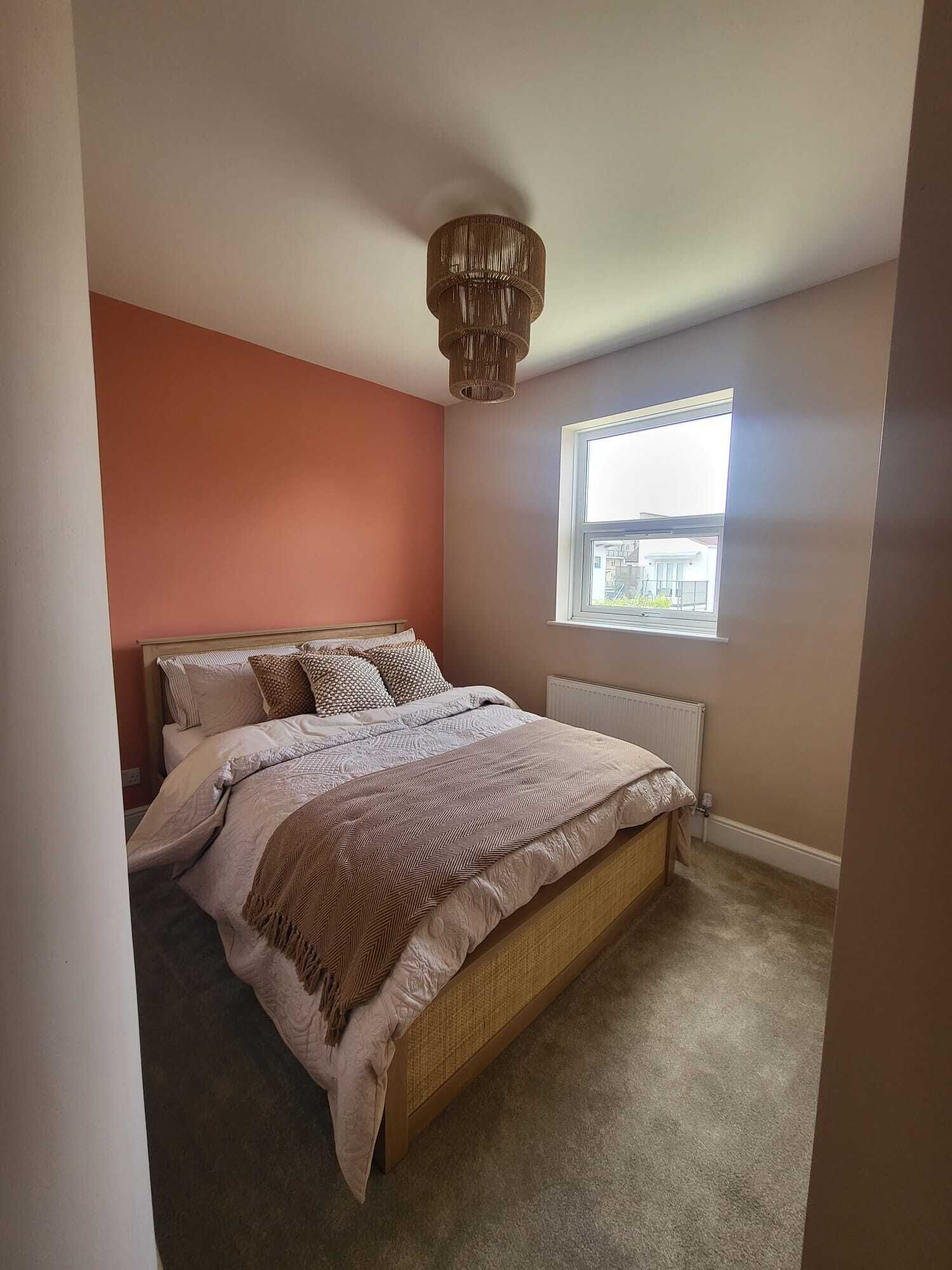 Un dormitorio con cama, ventana y lámpara en el techo.