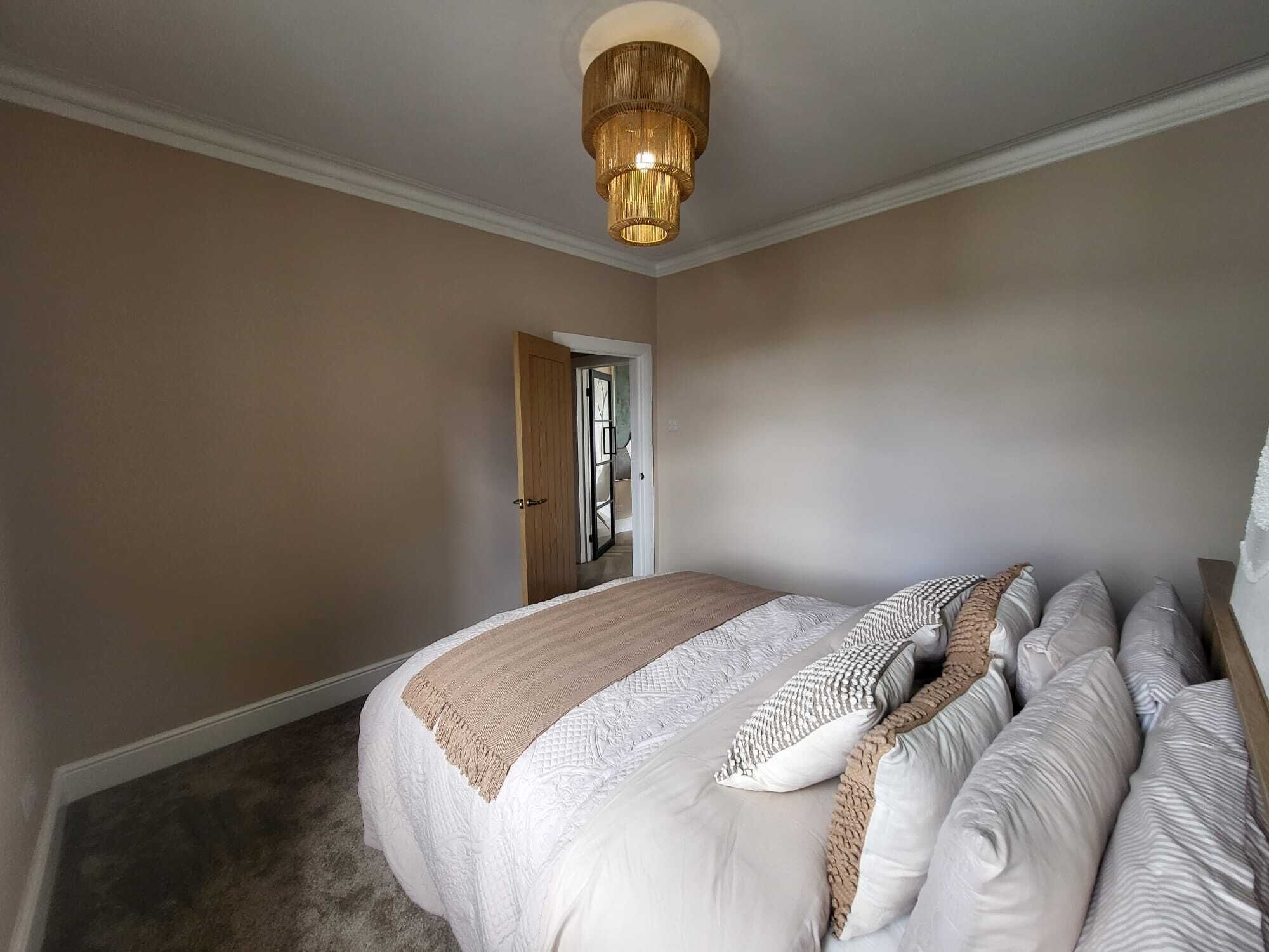 A bedroom with a bed, a door, and a ceiling light fixture.
