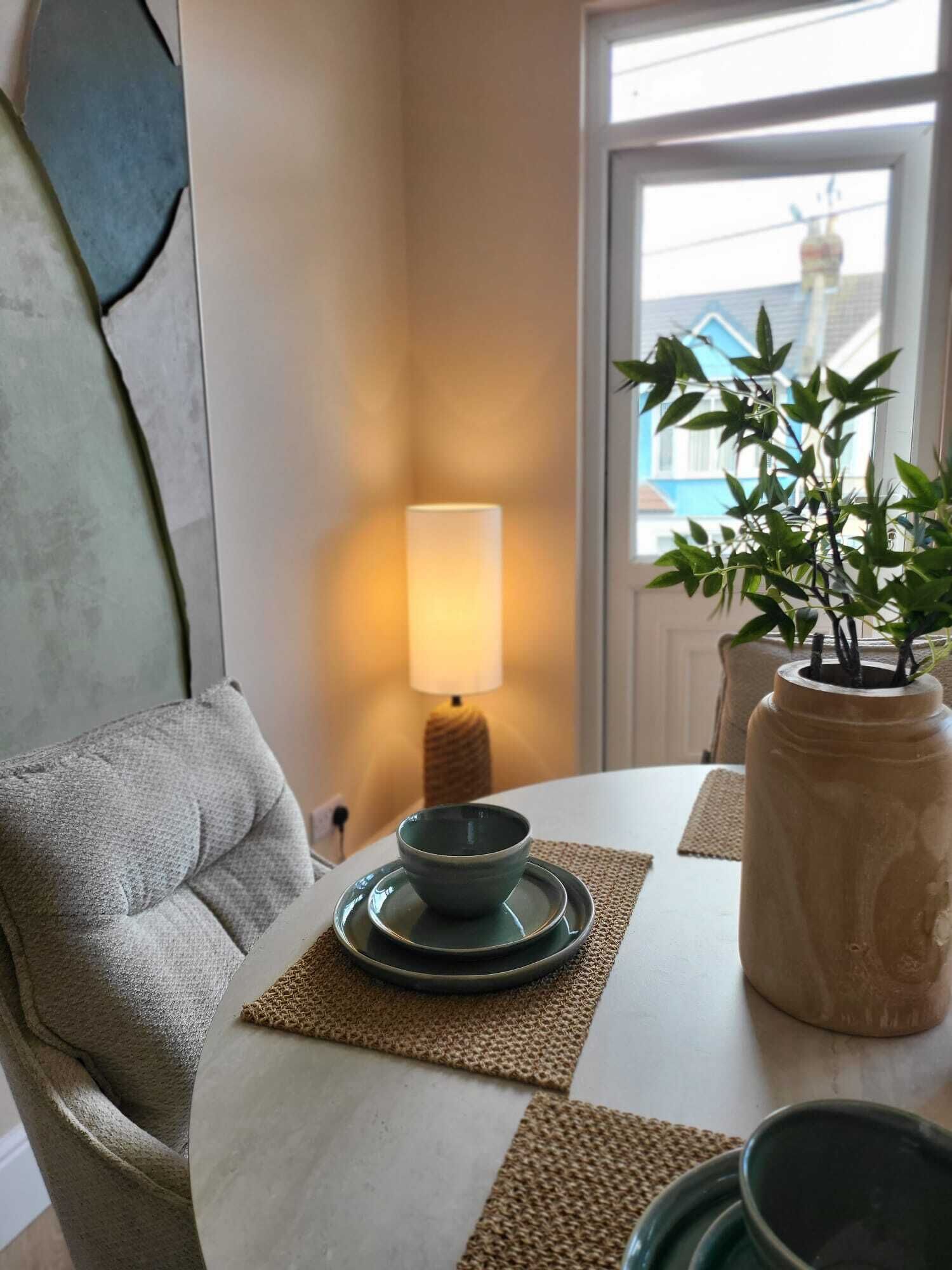 Ein Essbereich mit Tisch, Stühlen, einer Lampe und einem Blumentopf.