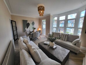A modern living room with a sofa set, a coffee table, and a dining area with chairs and a table.
