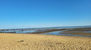 Ein Strand mit Booten, einer Holzsteganlage und einem klaren Himmel.
