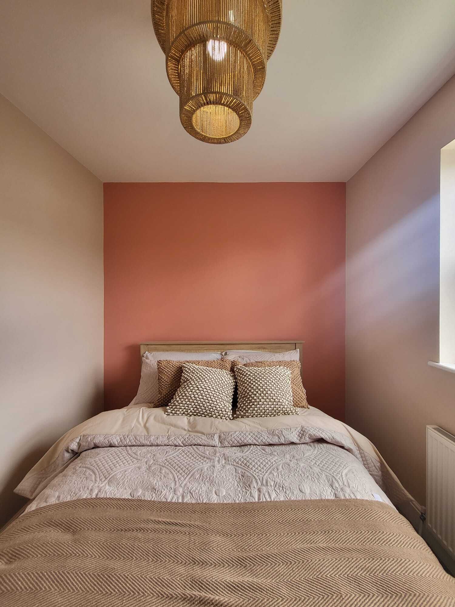 A bedroom with a bed, a patterned bedspread, and a textured wall.