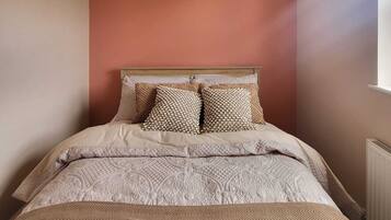 A bedroom with a bed, a patterned bedspread, and a textured wall.