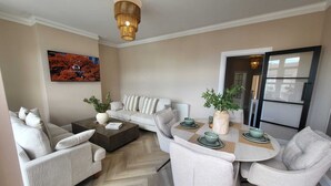 A modern living room with a sofa, chairs, a coffee table, and a dining table set for four.