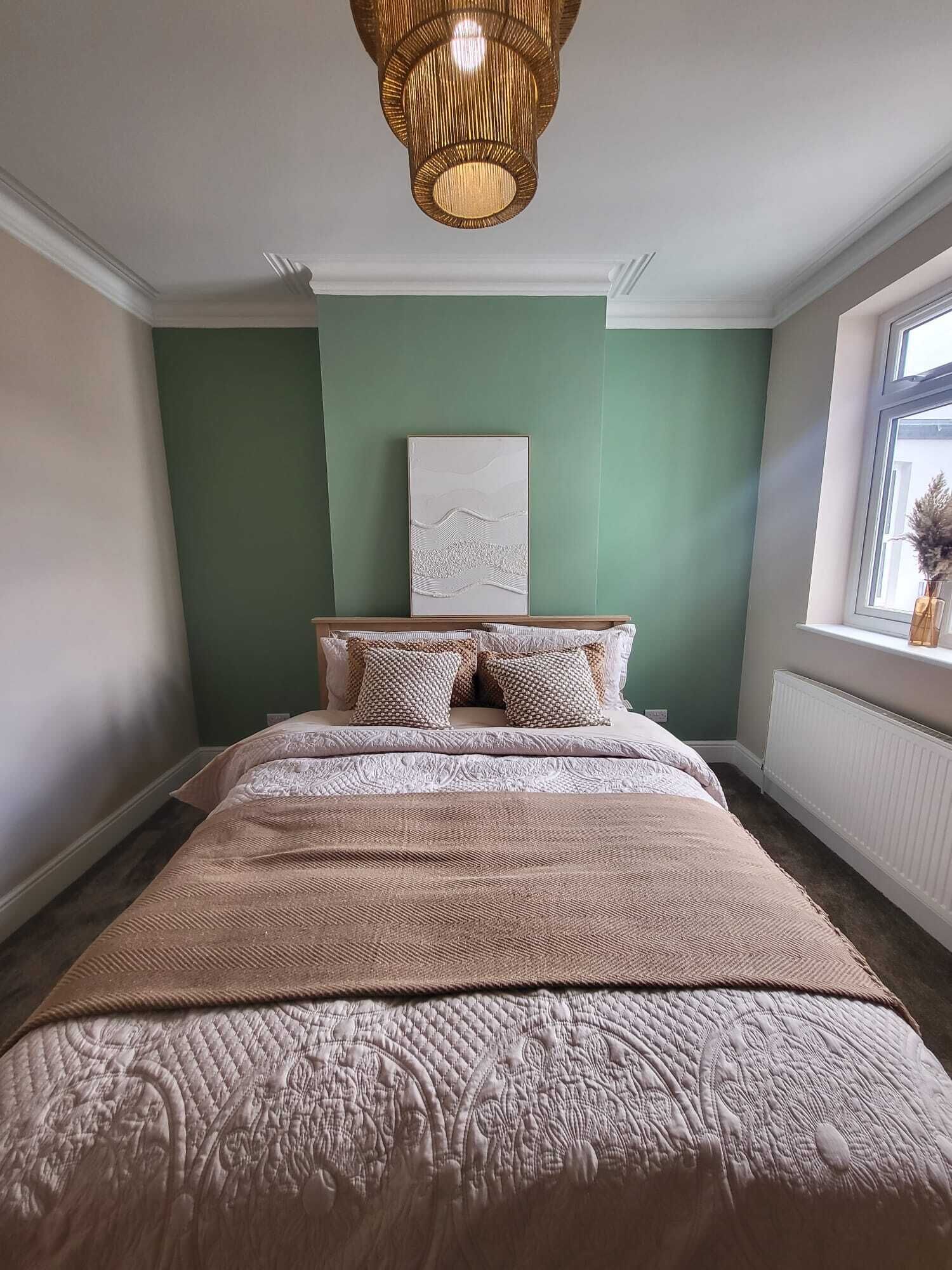 Une chambre à coucher avec un lit, une fenêtre et une œuvre d’art accrochée au mur.