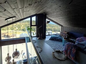 Ein Zimmer mit großem Fenster, einem Bett, einer Pflanze und einer Treppe.
