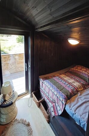 A cozy room with a bed, a window, and a door leading outside. - Spacious cabin with views, sauna and fireplace (Fåvang)