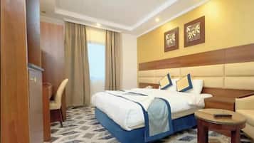 Una habitación de hotel con cama, escritorio, silla y una pequeña mesa.