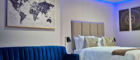 Een moderne hotelkamer met een wereldkaart als kunstwerk, een blauwe bank, een bed met witte beddengoed en een decoratietafel.