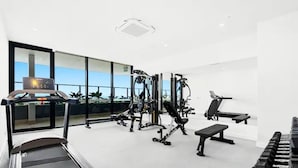 A modern gym with a treadmill, weight machines, and a bench. - Luxury Apartment Perfect for Holidays on the Coast (Gold Coast)