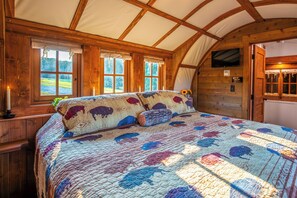 Een gezellige kamer met een groot bed, houten balken en uitzicht op de omgeving.