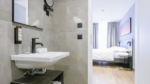 Ein modernes Badezimmer mit einem großen Spiegel, einem Waschbecken und einer Toilette.