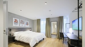 Ein modernes Hotelzimmer mit Bett, Schreibtisch und Fernseher.