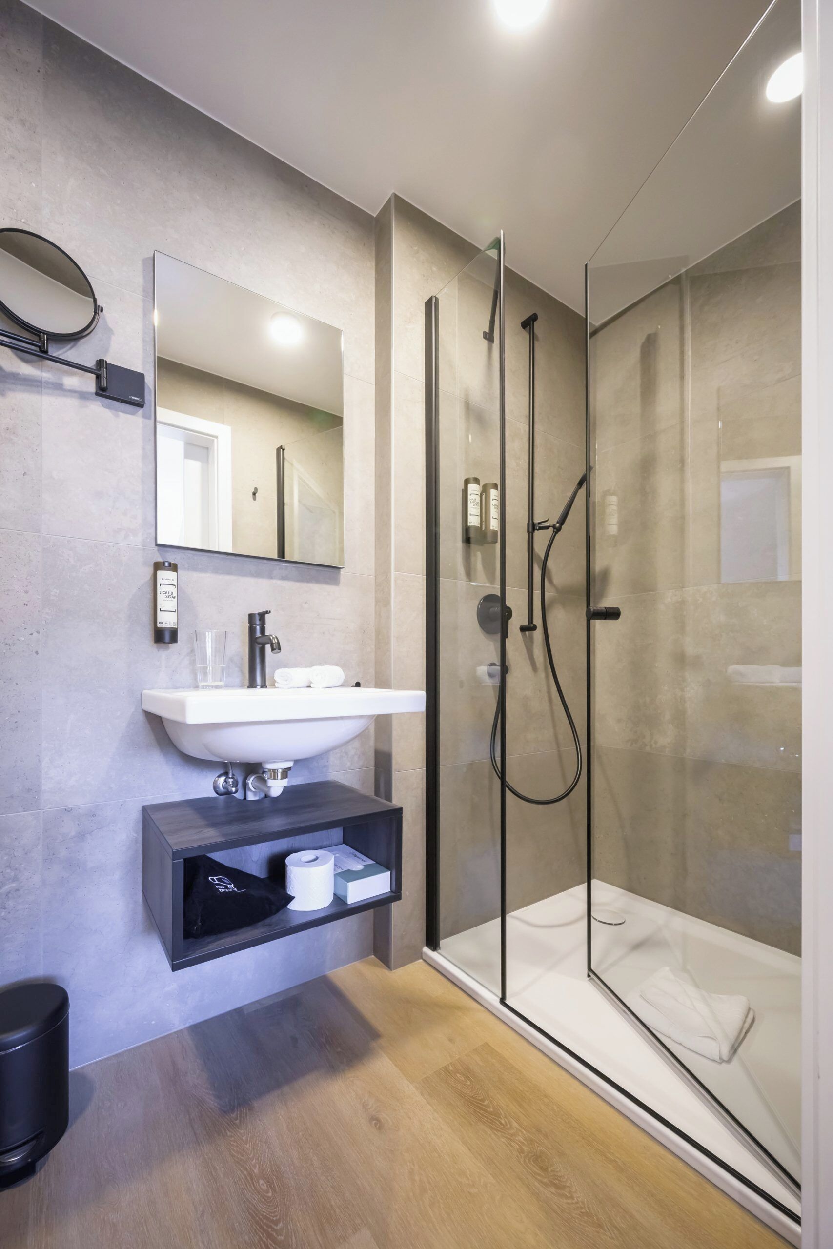Un baño moderno con ducha acristalada, un lavabo blanco y un espejo encima.