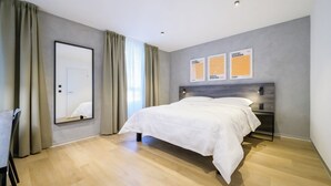 Ein modernes Schlafzimmer mit einem Bett, einem großen Spiegel und drei Bildern an der Wand.