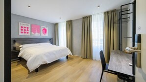 Ein modernes Hotelzimmer mit einem Bett, einem Schreibtisch und einem Stuhl.