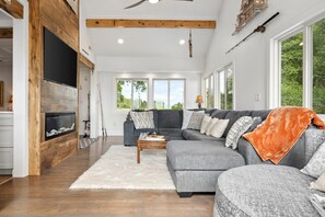 A modern living room with a fireplace, a large grey sectional sofa, and a white rug.