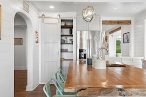 Une cuisine moderne avec un îlot central en bois, des meubles blancs et un luminaire suspendu.