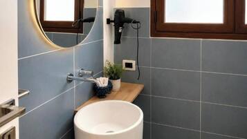 A bathroom with a white sink, a towel rack, a hairdryer, and a window.
