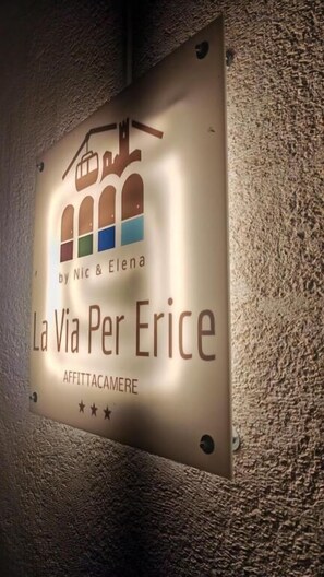Un cartel con la inscripción 'La Via Per Erice' y 'AFFITTACAMERE', indicando el tipo de habitación.
