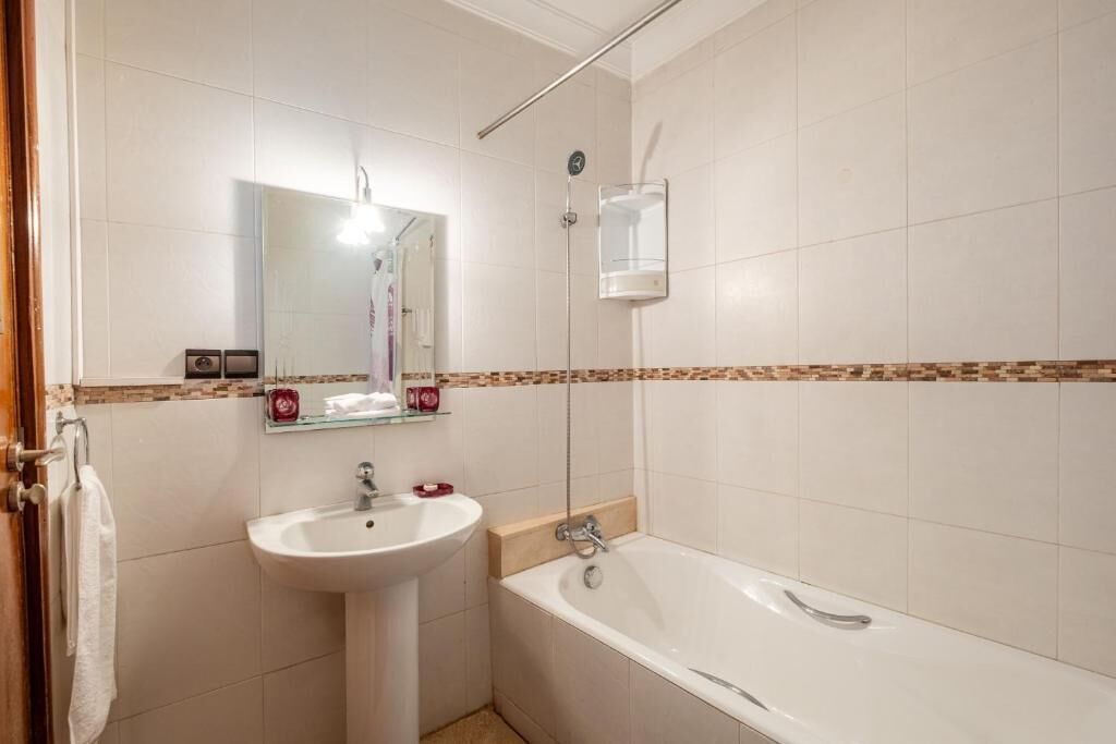 Une salle de bain avec un lavabo, un miroir et une baignoire.