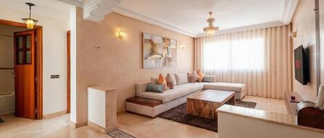 A modern living room with a sectional sofa, a coffee table, and a flat-screen TV.