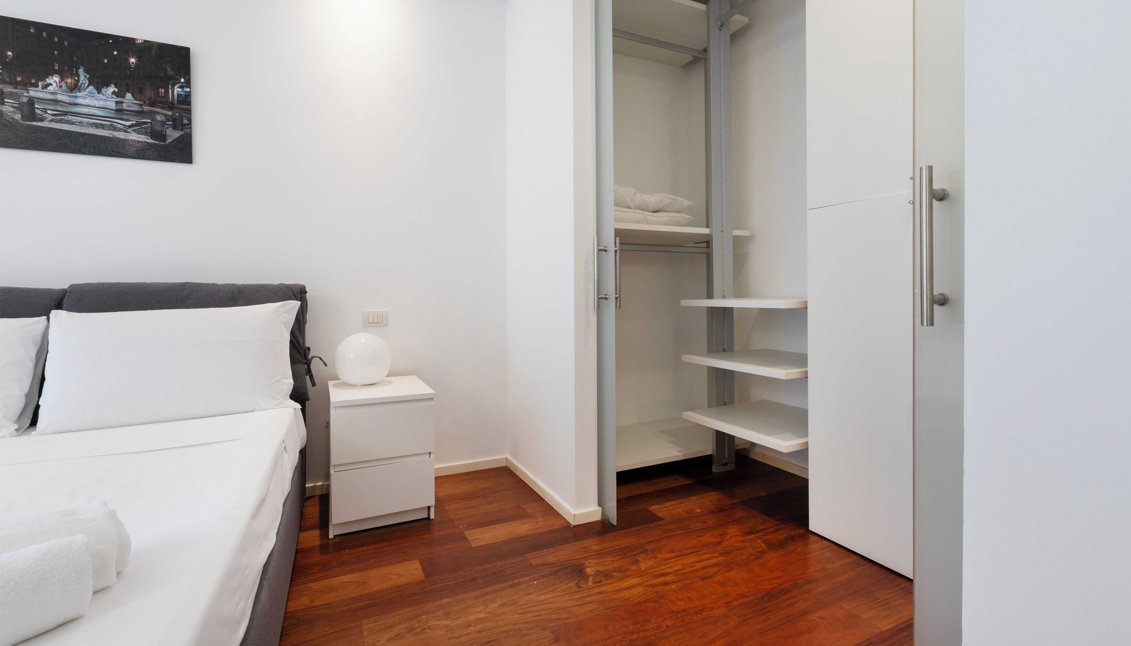 A bedroom with a bed, bedside table, and a nightstand.