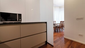 Una cocina moderna con microondas, armarios y un comedor con sillas y una mesa.