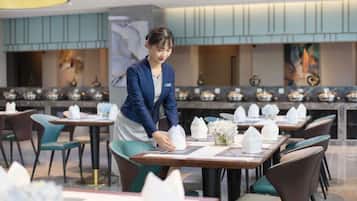 A restaurant setting with tables set for dining, a waiter attending to a table, and a modern interior design.